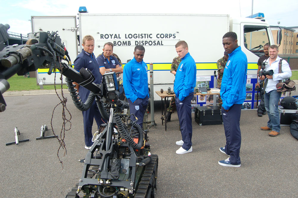 Danny Rose (left), Tom Cleverley and Danny Welbeck (right) study a bomb disposal unit.